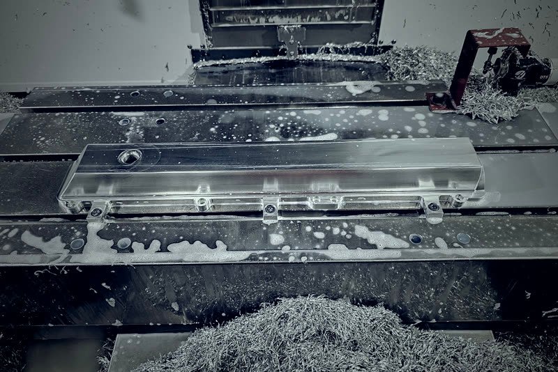 Frezowanie CNC płyty aluminiowej, wióry w przestrzeni roboczej maszyny