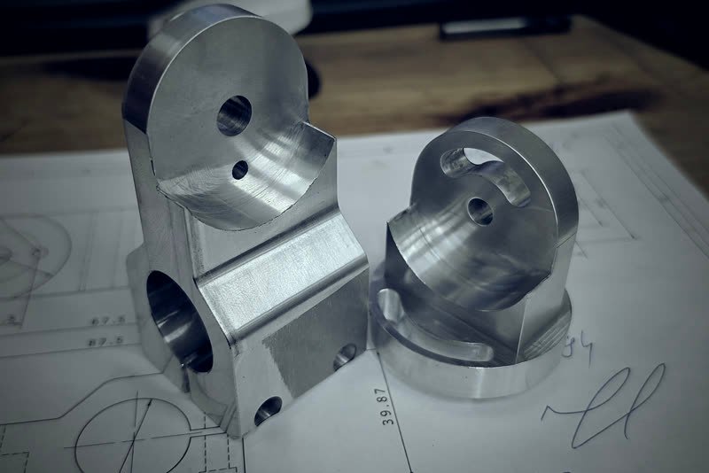 Prototypowe detale aluminiowe leżące na rysunku technicznym